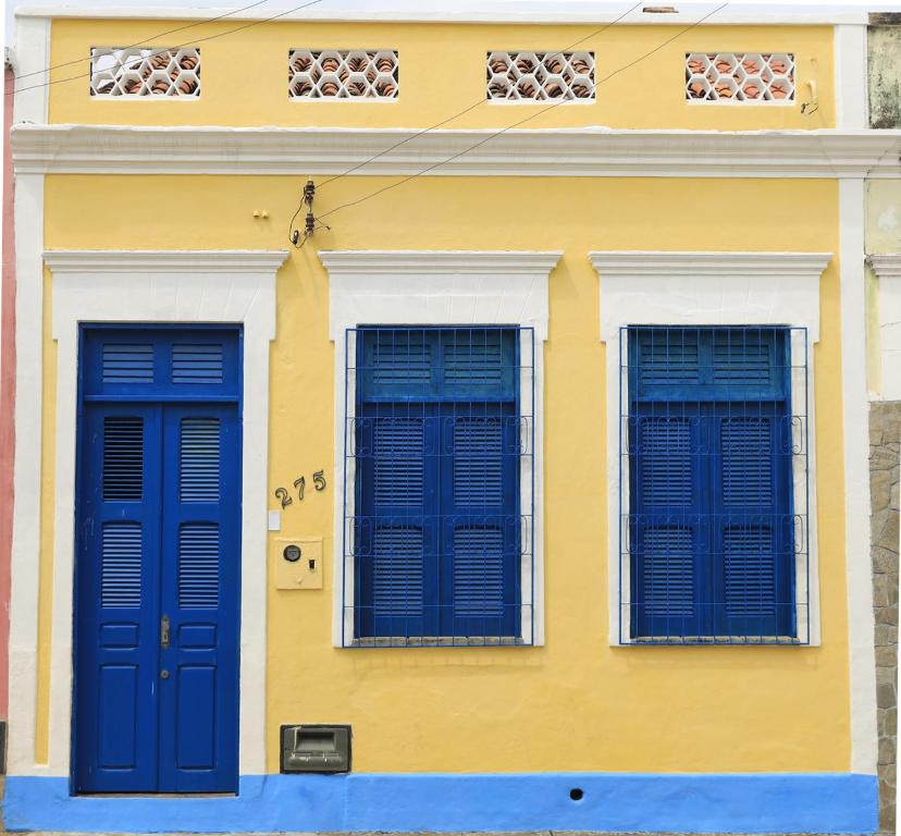 two blue doors on a yellow building with windows at Casa Rústica e Aconchegante em Camocim in Camocim