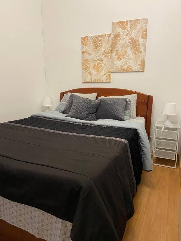 a bedroom with a large bed with a black blanket at Casa de Vasco-Estadia Familiar e Tranquila in Amora