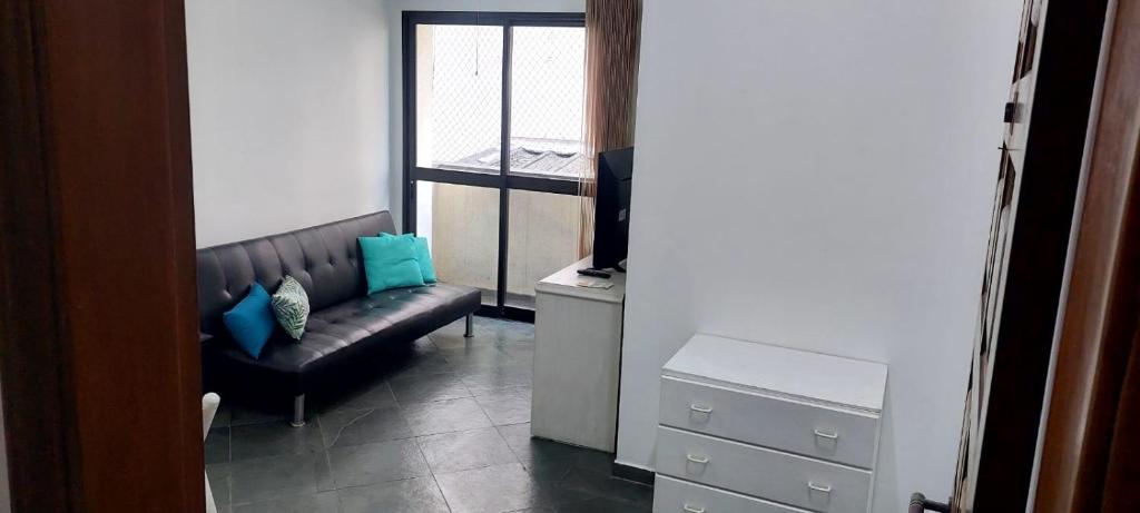 a living room with a couch and a television at Apartamento em Enseada Guarujá in Guarujá