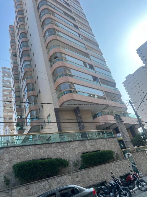 a tall building with motorcycles parked in front of it at Apto com Ar condicionado e churrasqueira in Praia Grande