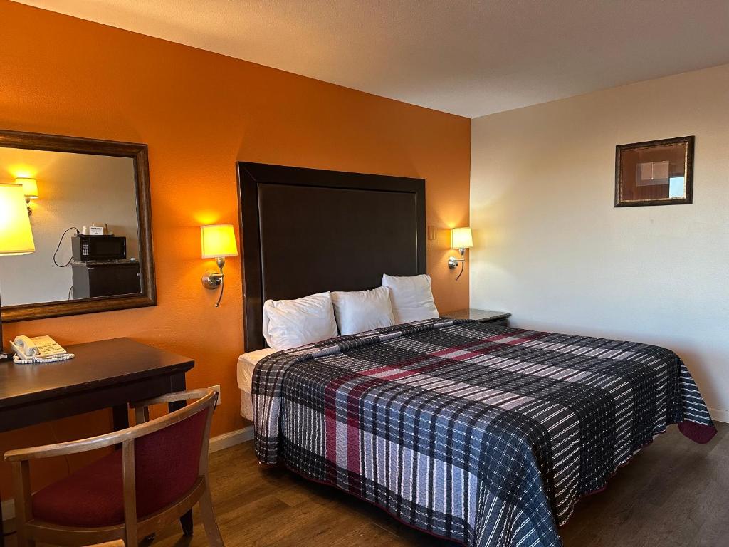 ein Hotelzimmer mit einem Bett, einem Schreibtisch und einem Spiegel in der Unterkunft Regal Inn Las Vegas New Mexico in Las Vegas