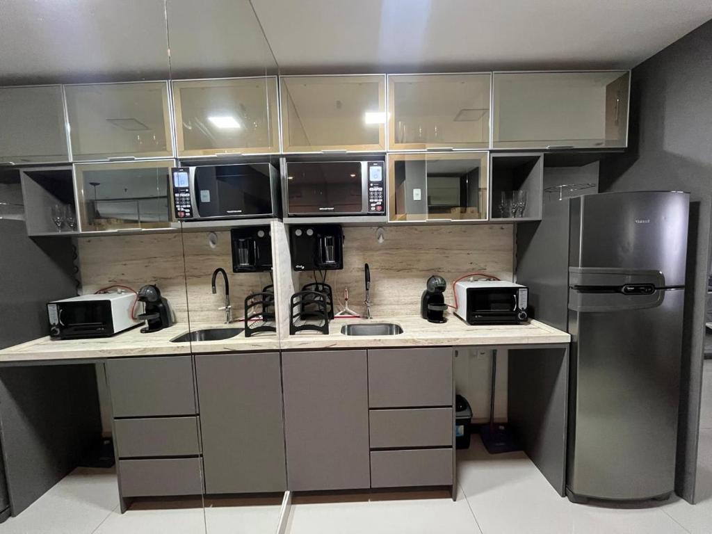a kitchen with a counter with microwaves and a refrigerator at M&V Flats - Prédio Vision - 1,5 km Mané Garrincha - 500m Esplanada dos Ministérios - Vaga de garagem - Ar condicionado - Cama queen size - Piscina - Academia in Brasilia