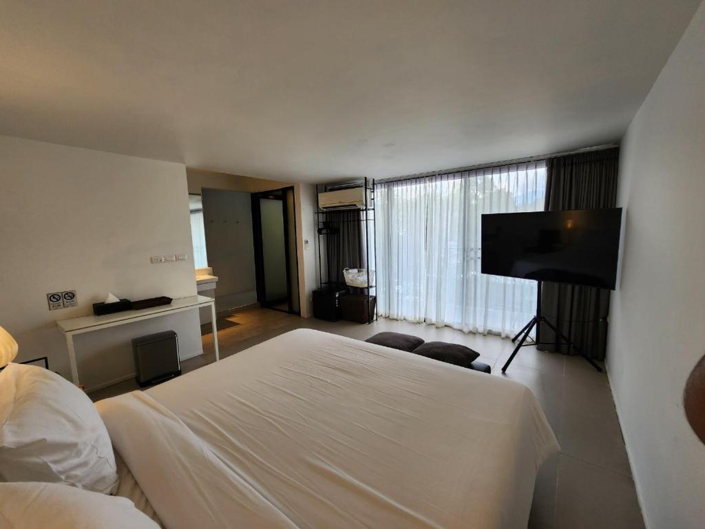 A large-bed room with a wall-mounted TV, minibar, air conditioner and full-width window.