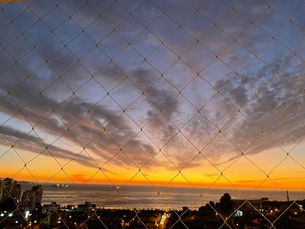 a fence with a sunset in the background at Departamento Familiar con vista al Mar in Viña del Mar