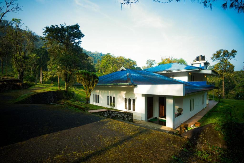 Casspo Forest Bungalow في Kallar Vattiyar: بيت ابيض بسقف ازرق وطريق