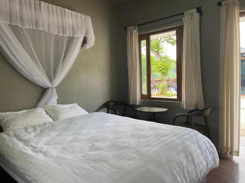 a bedroom with a white bed and a window at Gem Market Homestay in Yên Bình