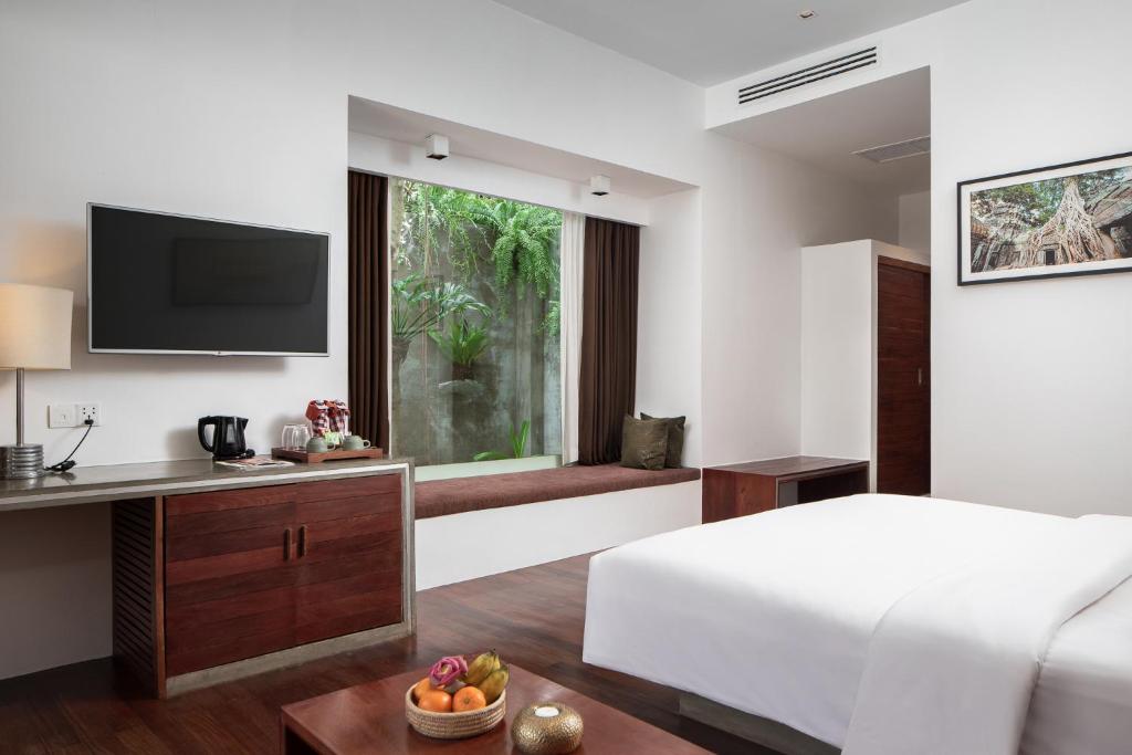a bedroom with a bed and a desk and a window at Lynnaya Urban River Resort in Siem Reap