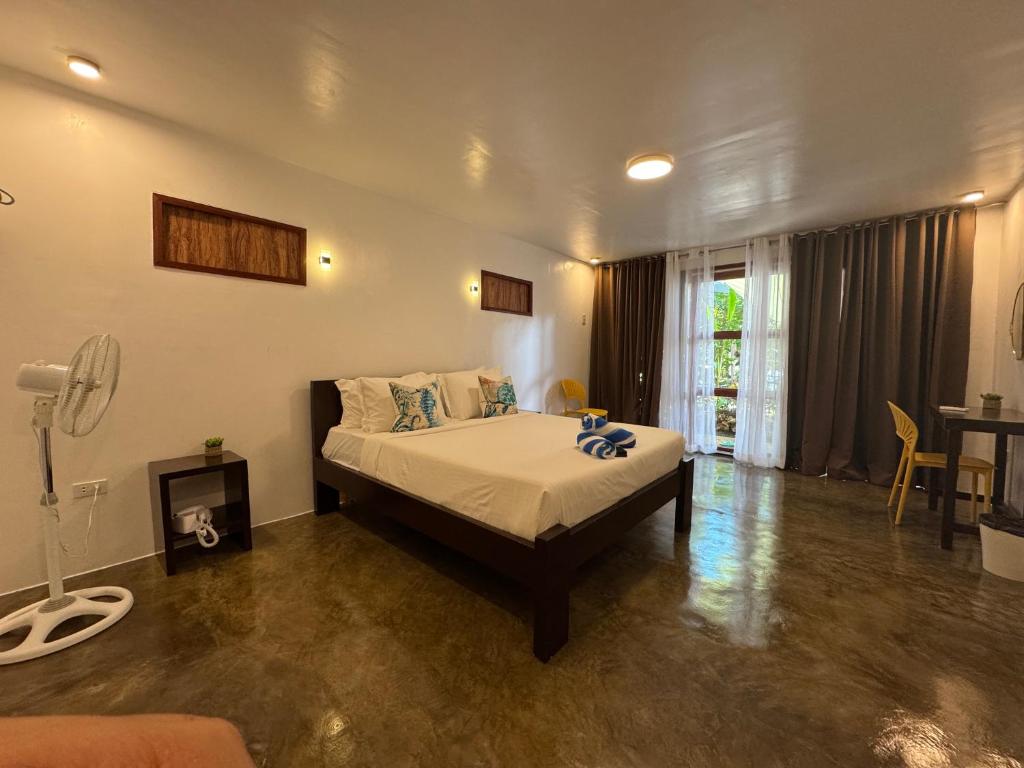 a bedroom with a bed and a table and a window at NUTMEG Cottage Siargao- Private room in General Luna