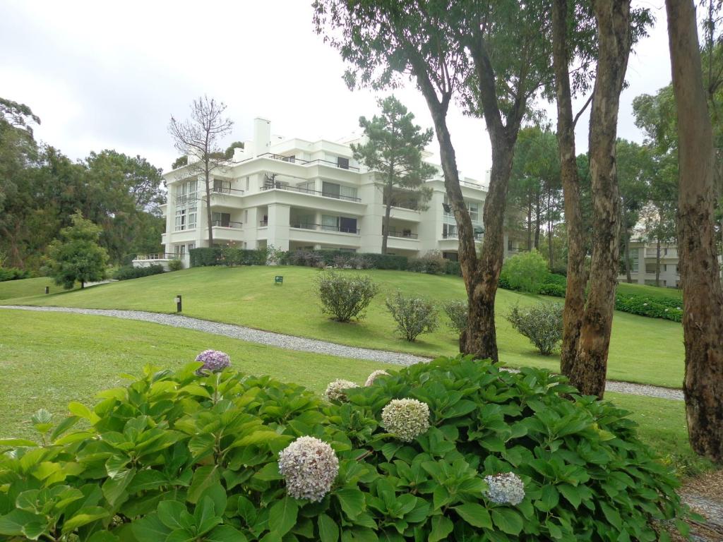 a large white house on a hill with bushes at Green Park Exclusive Apartment in Punta del Este