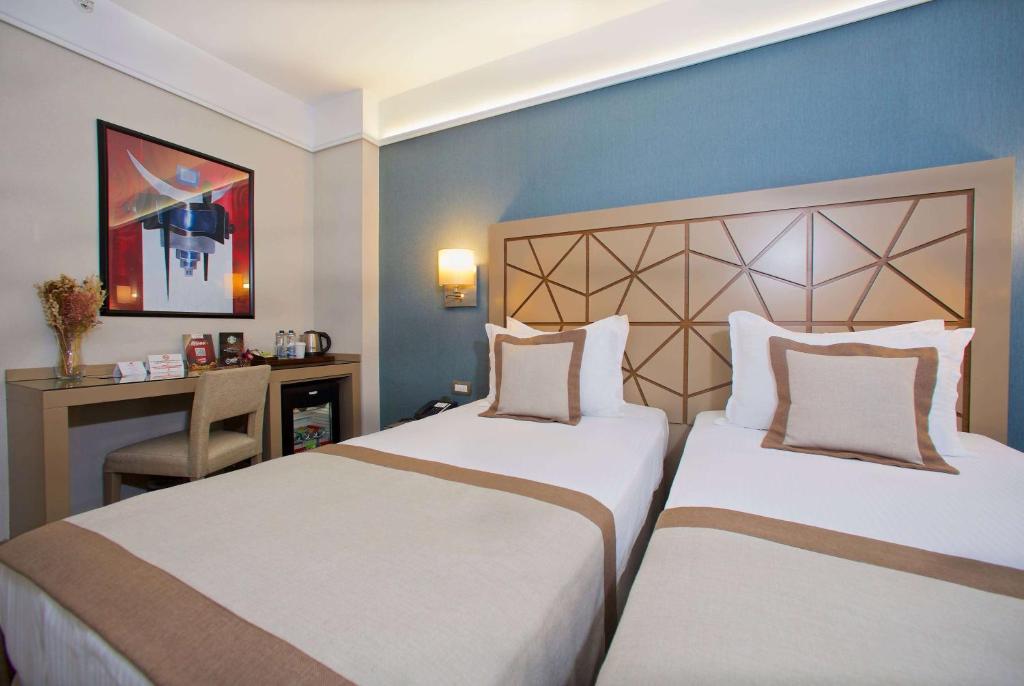 a hotel room with two beds and a desk at Ramada By Wyndham İstanbul Taksim in Istanbul