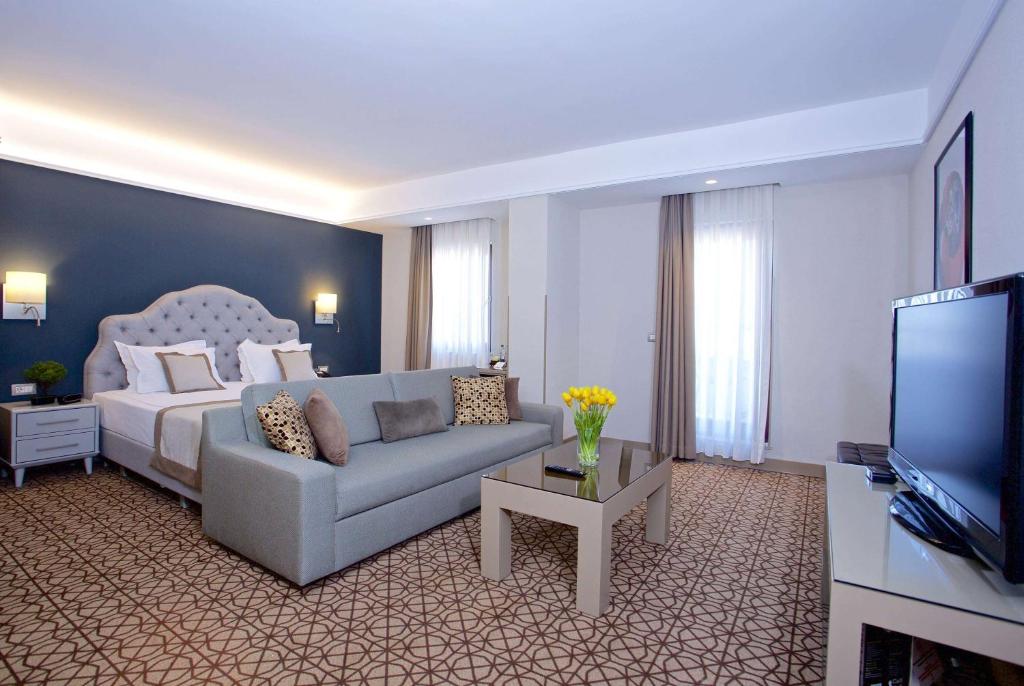 a living room with a couch and a bed and a television at Ramada By Wyndham İstanbul Taksim in Istanbul