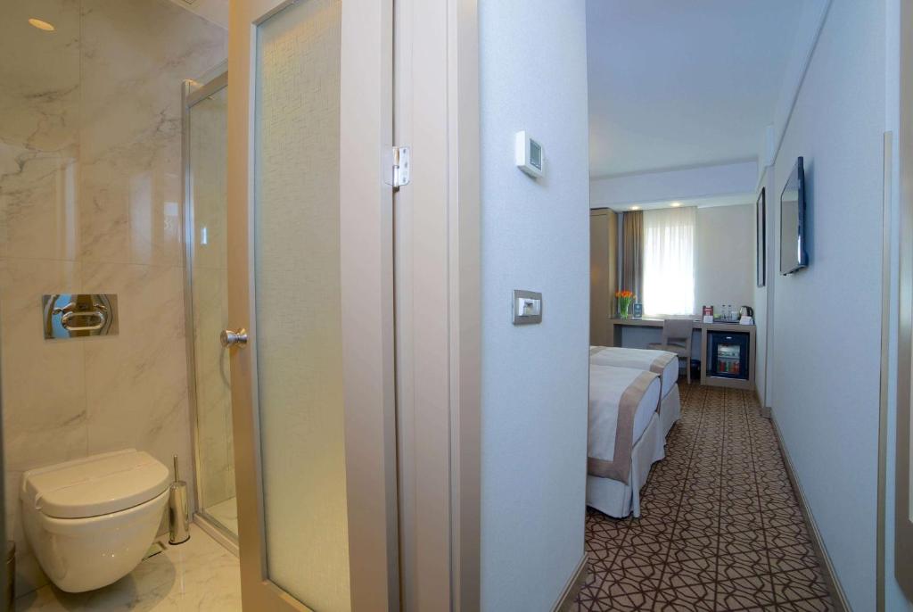 a bathroom with a toilet and a bed in a room at Ramada By Wyndham İstanbul Taksim in Istanbul