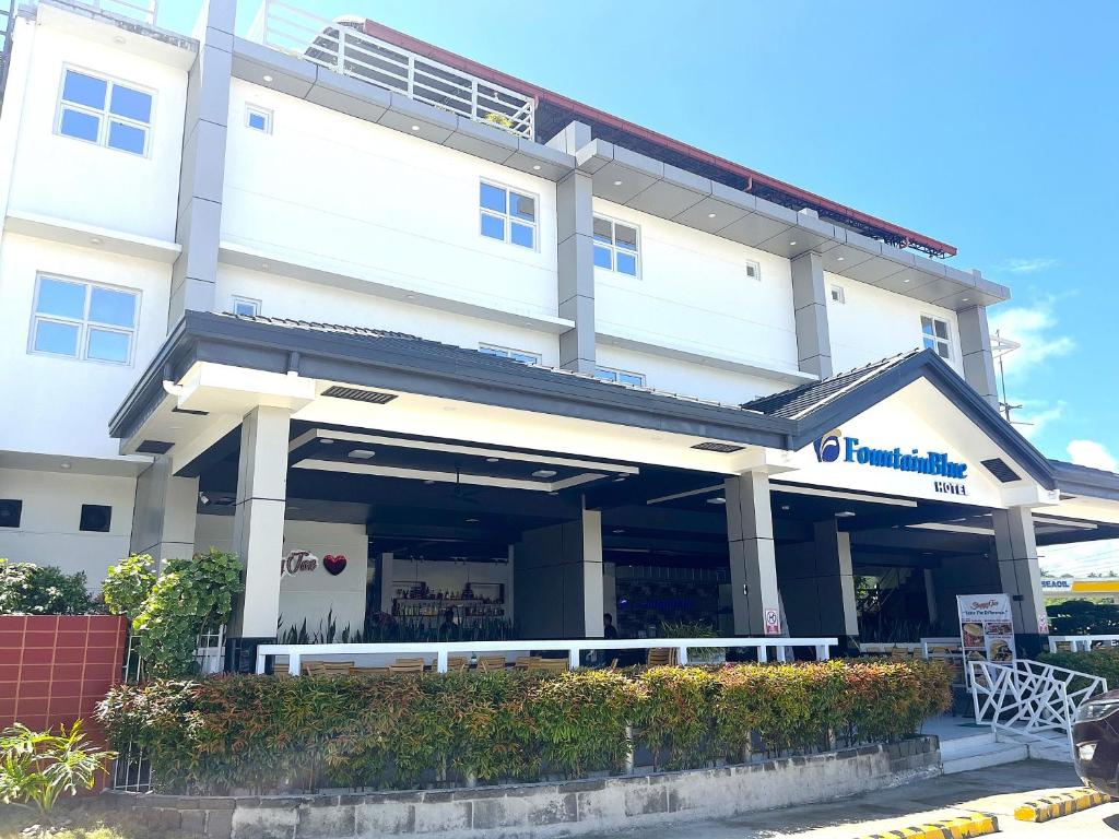 a white building with a restaurant in front of it at FountainBlue Hotel and Banquet Hall in Daraga