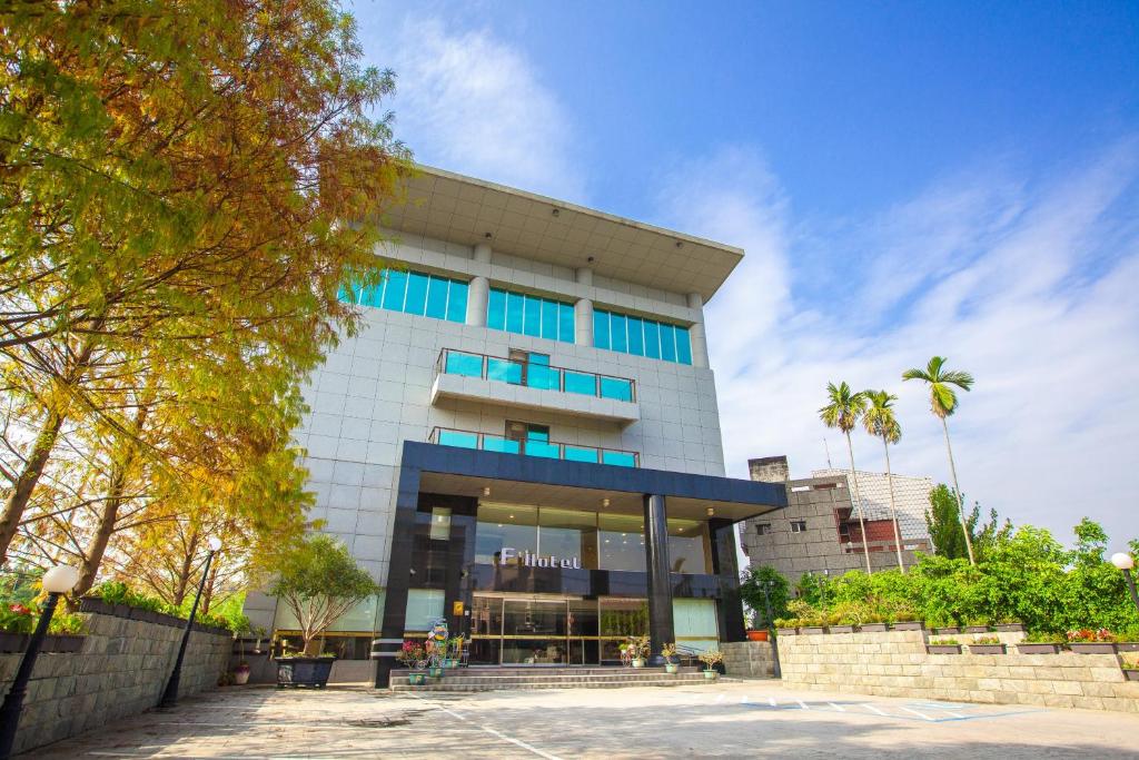 - un bâtiment blanc avec des fenêtres bleues et des palmiers dans l'établissement F Hotel - Chiayi, à Fanlu