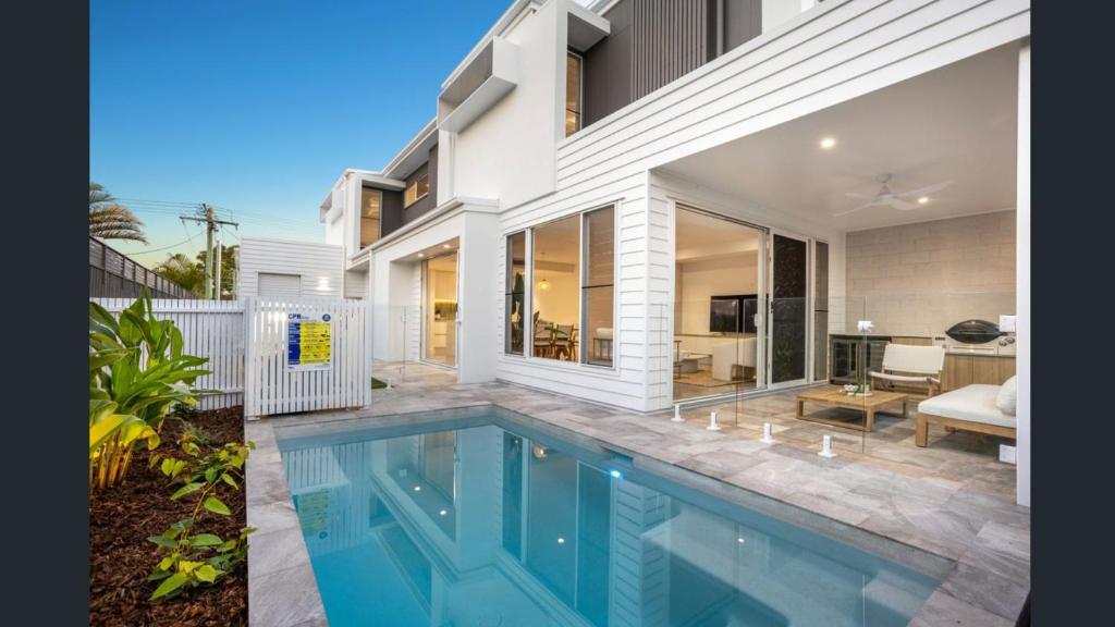 a swimming pool in front of a house at Luxury Townhouse Maroochydore in Maroochydore
