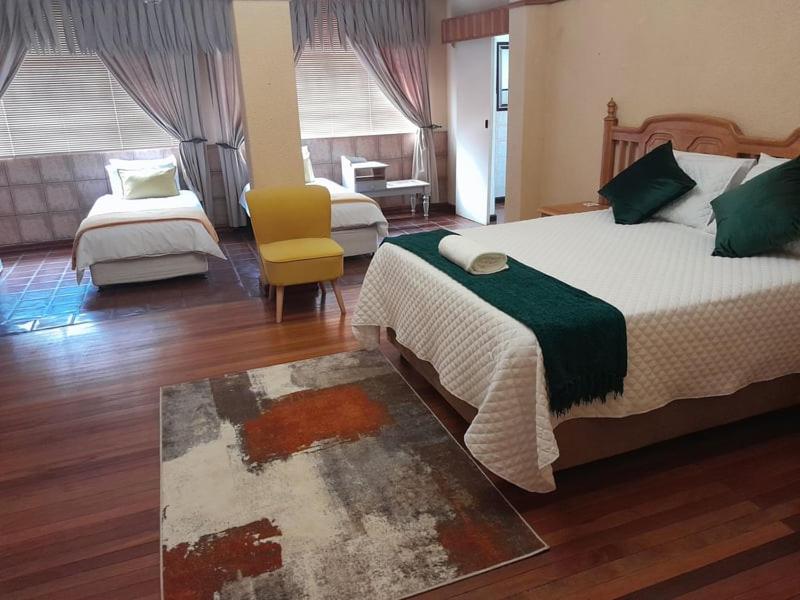 a hotel room with two beds and a chair at morning sun guesthouse in Hartswater