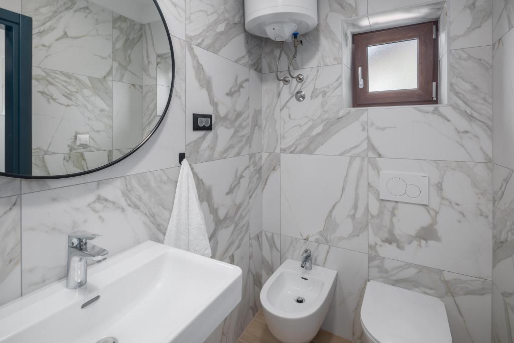 a bathroom with a sink and a toilet and a mirror at Apartments Špadići in Poreč