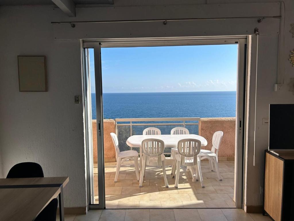 une table et des chaises sur un balcon avec l'océan dans l'établissement Lea-Vue mer panoramique- clim-Wifi- plage à pieds, à Conca