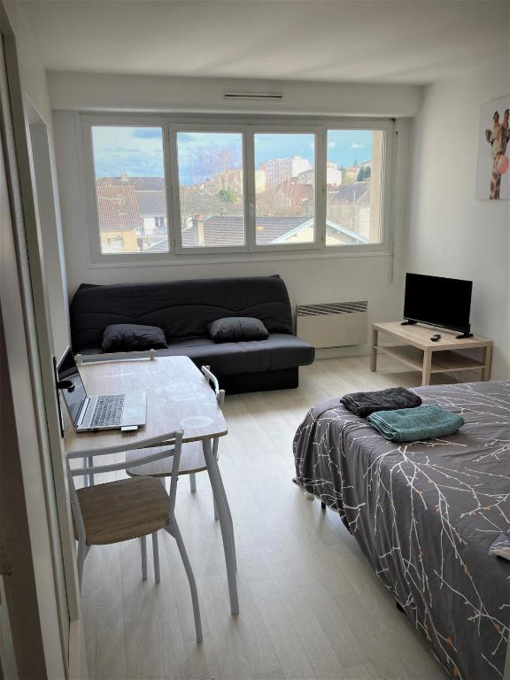 une chambre avec un lit et une table avec un ordinateur portable dans l'établissement Appartement double 13 à Limoges, à Limoges