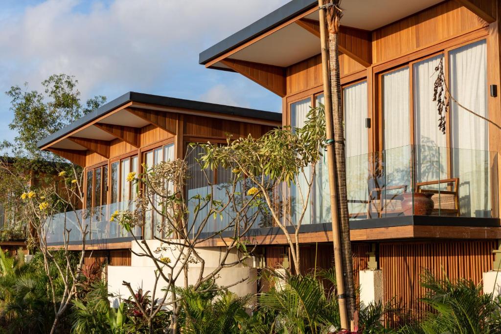 a house with a wrap around porch with a balcony at Grün Resort Uluwatu in Uluwatu