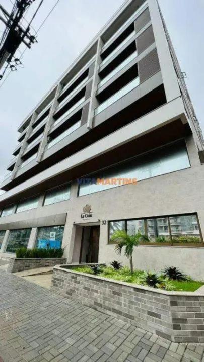 a tall building with a palm tree in front of it at Apt a 500m da praia do forte in Cabo Frio