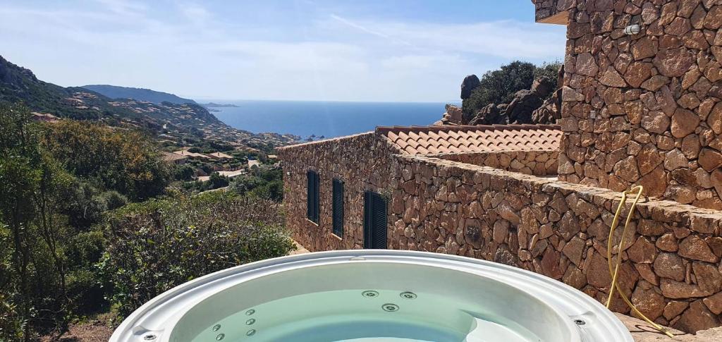a bath tub in front of a stone building at Roccette OndaTURCHESE, Vista Mare e Jacuzzi Privata in Costa Paradiso
