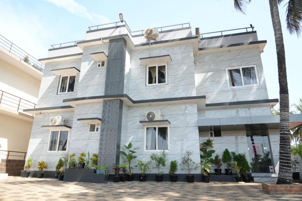 Un edificio blanco con palmeras delante. en Amani Beach Homestay, en Māvalli