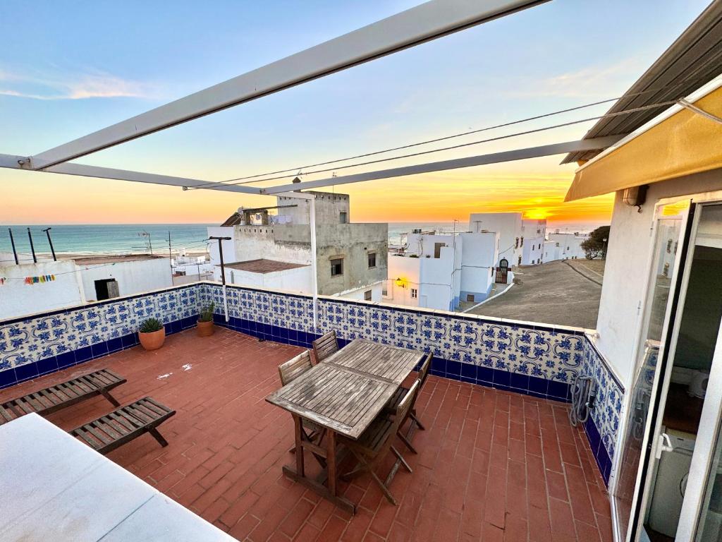 d'une terrasse avec une table et des bancs donnant sur l'océan. dans l'établissement Azucena luxury town house in Conil with terrace and great views, à Conil de la Frontera