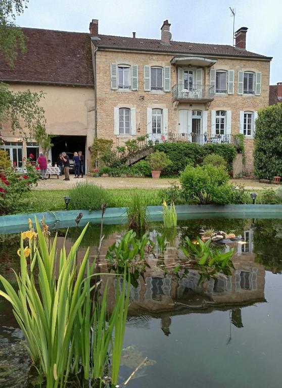 une vieille maison avec un étang en face de celle-ci dans l'établissement Beautiful 18th Century Whole Manor House with Sole Use Private Pool, à Gevingey