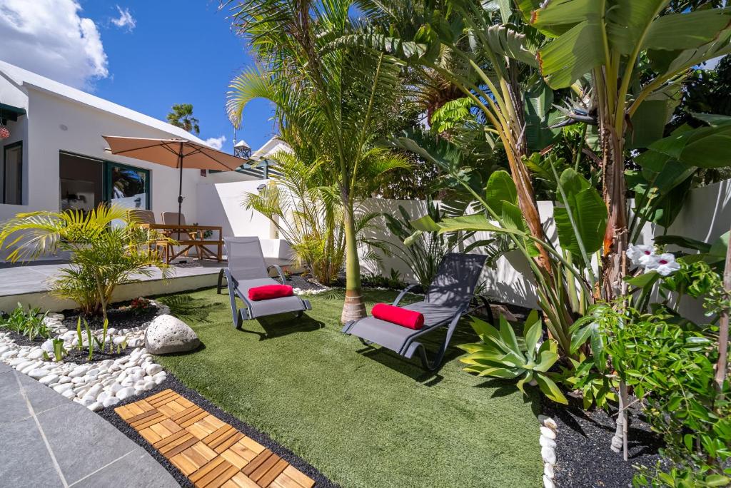 a backyard with lawn chairs and palm trees at Villa Las Marias Suite - Playa Roca Residence in Costa Teguise