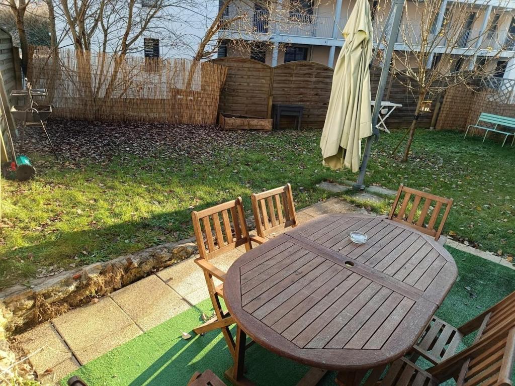 une table en bois, 2 chaises et un parasol dans l'établissement Centre ville jardin privatif, à Morteau