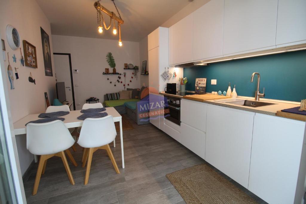 a kitchen with white cabinets and a table and chairs at Appartamento San Marco in Cesenatico