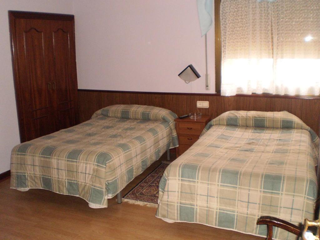 a bedroom with two beds and a window at Hostal Hilton in Burgos