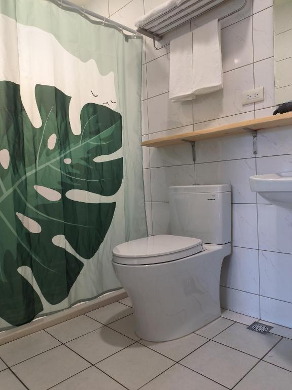 a bathroom with a toilet and a shower curtain at Kinmen Fujian Homestay in Tung-chou