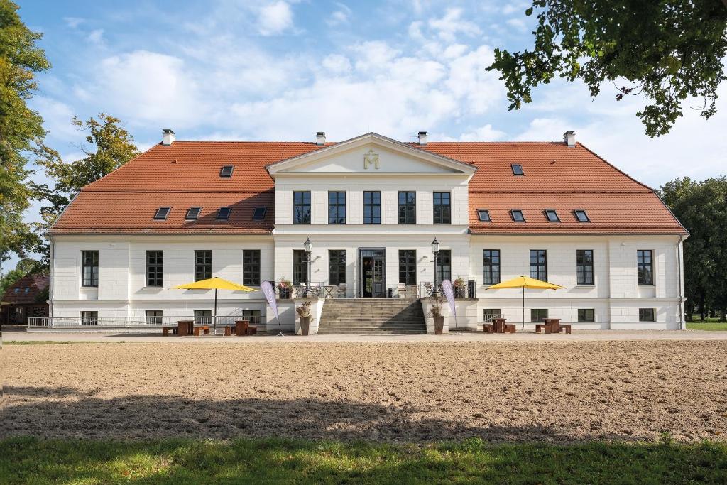 un grande edificio bianco con ombrelloni gialli di fronte di Peter's Resort a Redefin