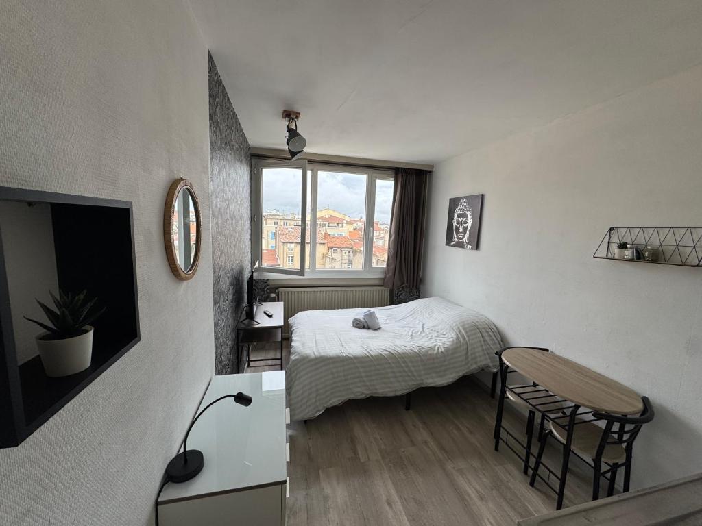 a bedroom with a bed and a table and a window at Studio au coeur de Valence 45 in Valence