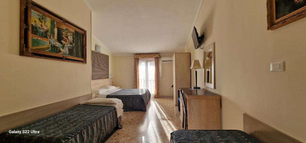 a hotel room with two beds and a desk at Hotel Chopin in Fiumicino