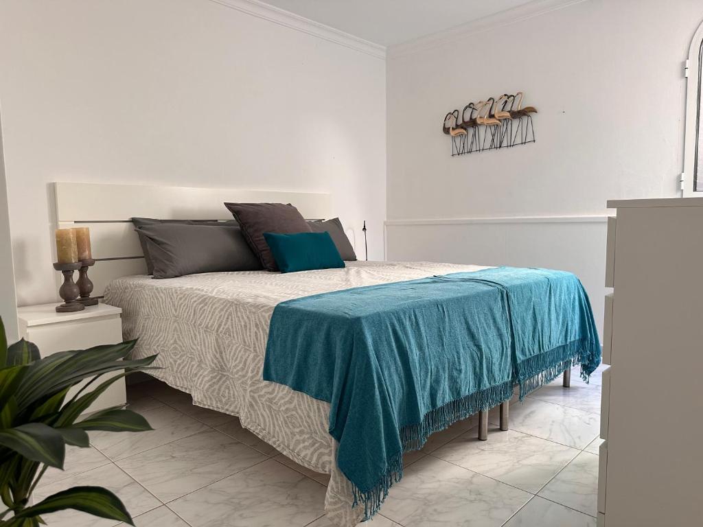 a bedroom with a bed with a blue blanket on it at Aquamarina Gran Canaria in Los Caideros