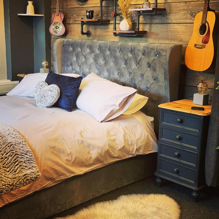 a bedroom with a bed with a guitar and a nightstand at Christmas Cottage in Doveridge