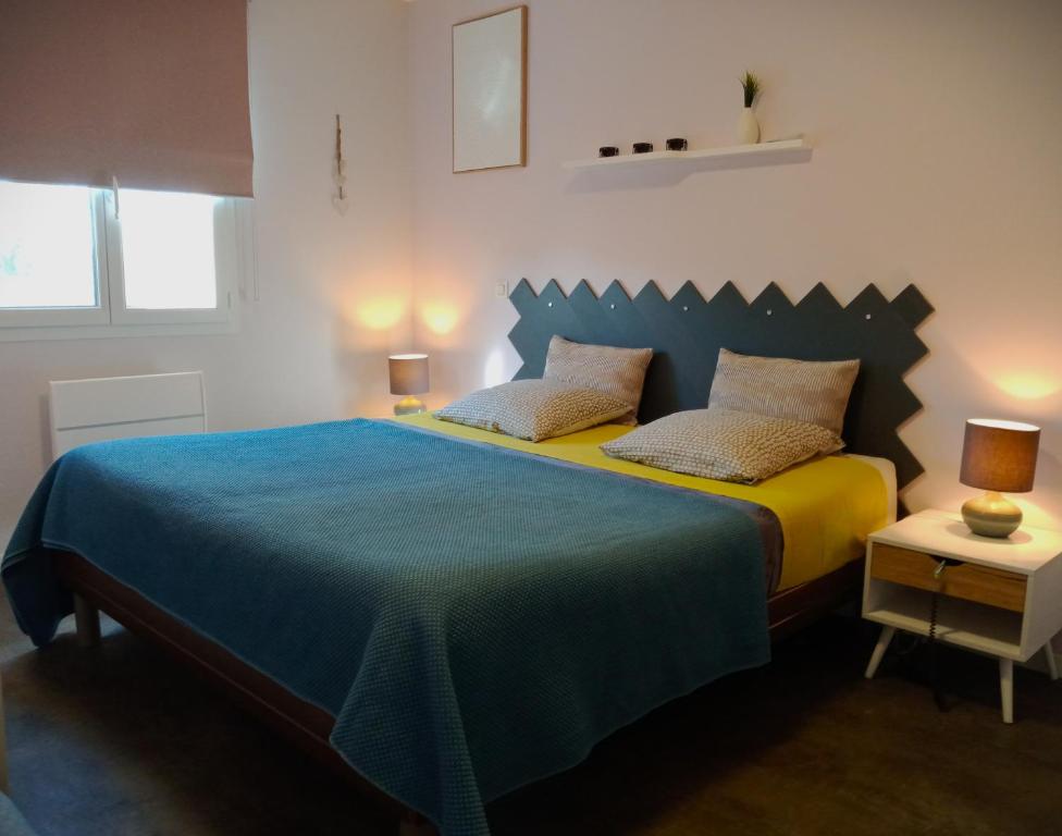 una camera con letto blu e giallo con due cuscini di Au petit lieu-dit a Anglade