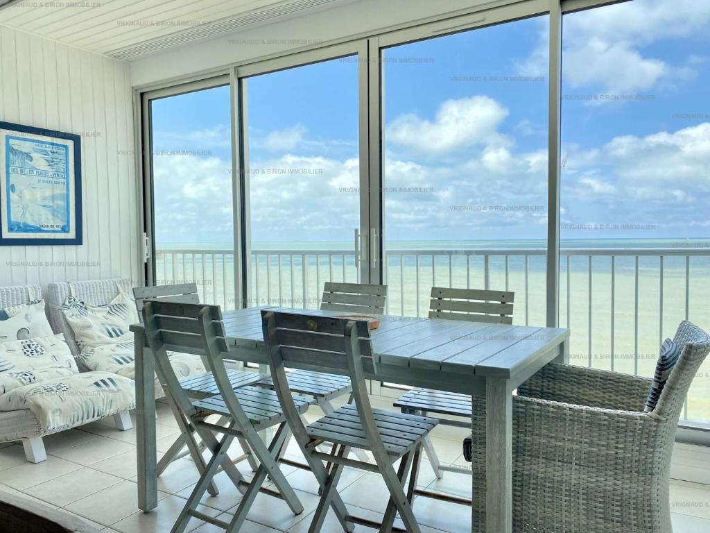 une table et des chaises sur un balcon avec vue sur l'océan dans l'établissement Bleu Marine Saint Gilles Croix de Vie, à Saint-Gilles-Croix-de-Vie