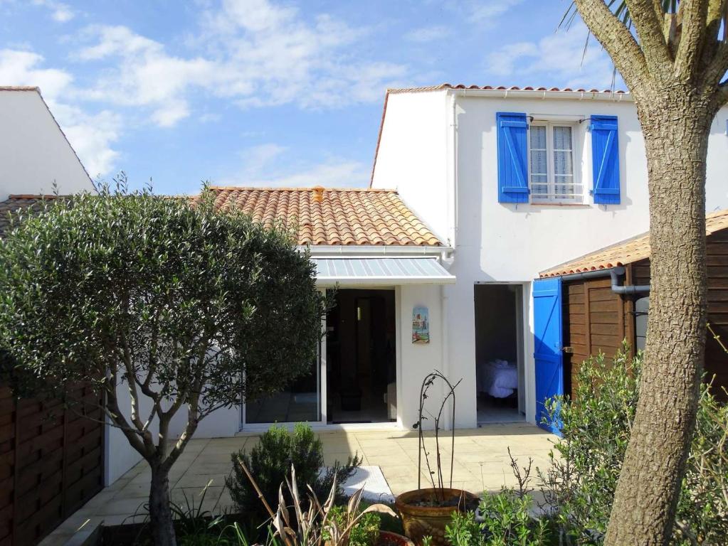 une maison blanche avec des volets bleus et un arbre dans l'établissement Nausicaa Saint Gilles Croix de Vie, à Saint-Gilles-Croix-de-Vie