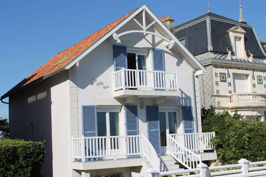 a white house with blue windows and balconies at Quatre Vents Saint Hilaire de Riez in Saint-Hilaire-de-Riez