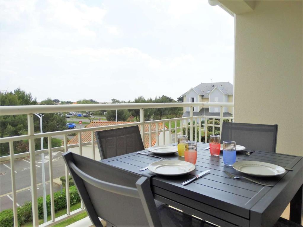 a black table with chairs and plates on a balcony at Gardénia Saint Gilles Croix de Vie in Le Sablais