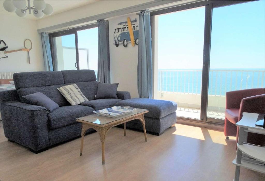 a living room with a blue couch and a table at Goélette Saint Gilles Croix de Vie in Le Sablais