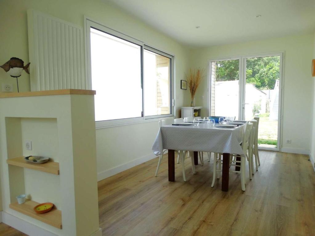 a dining room with a table with chairs and windows at Javeline Saint Hilaire de Riez in Sion-sur-lʼOcéan