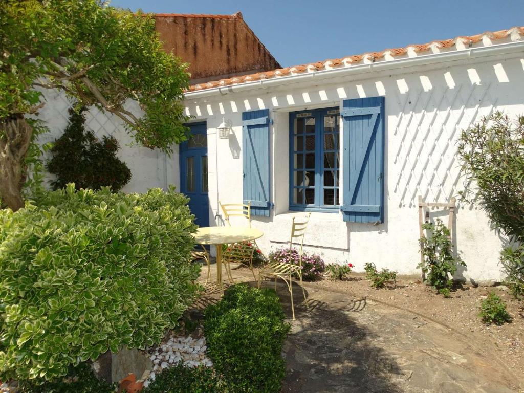une maison blanche avec des volets bleus et une table dans l'établissement La Grénette Saint Gilles Croix de Vie, à Saint-Gilles-Croix-de-Vie