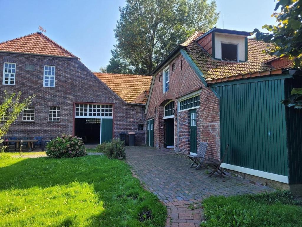 une ancienne maison en briques avec un garage vert dans l'établissement Ferienwohnung für 6 Personen in Moorhausen, à Varel