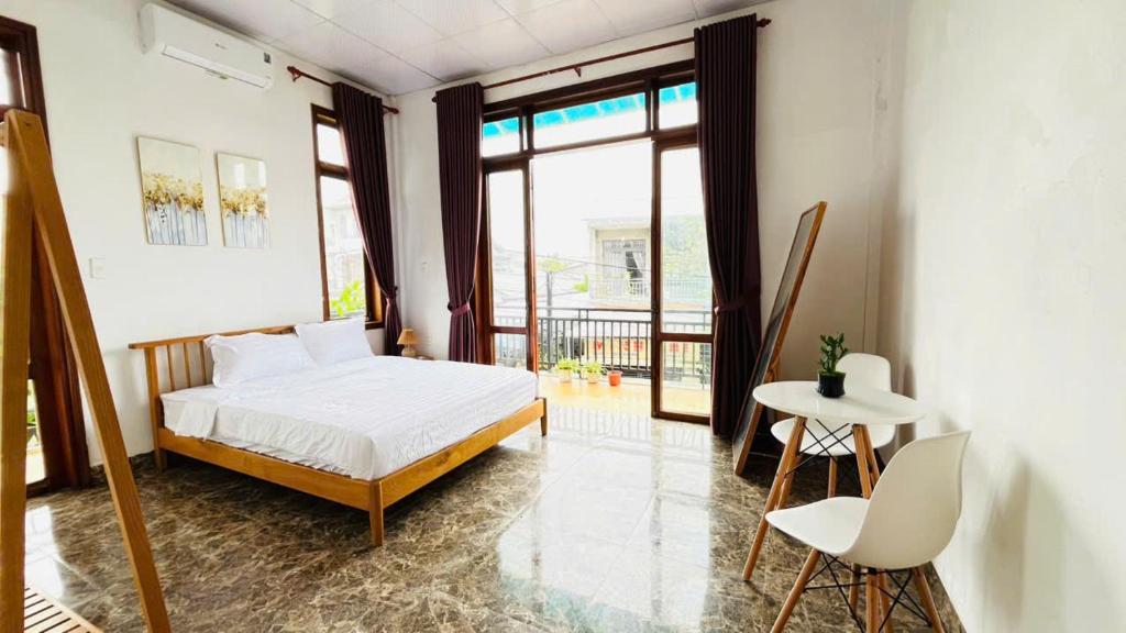 Un dormitorio con una cama y una mesa y sillas. en Vang's Homestay - Huế, en Ấp Long Hồ Hạ