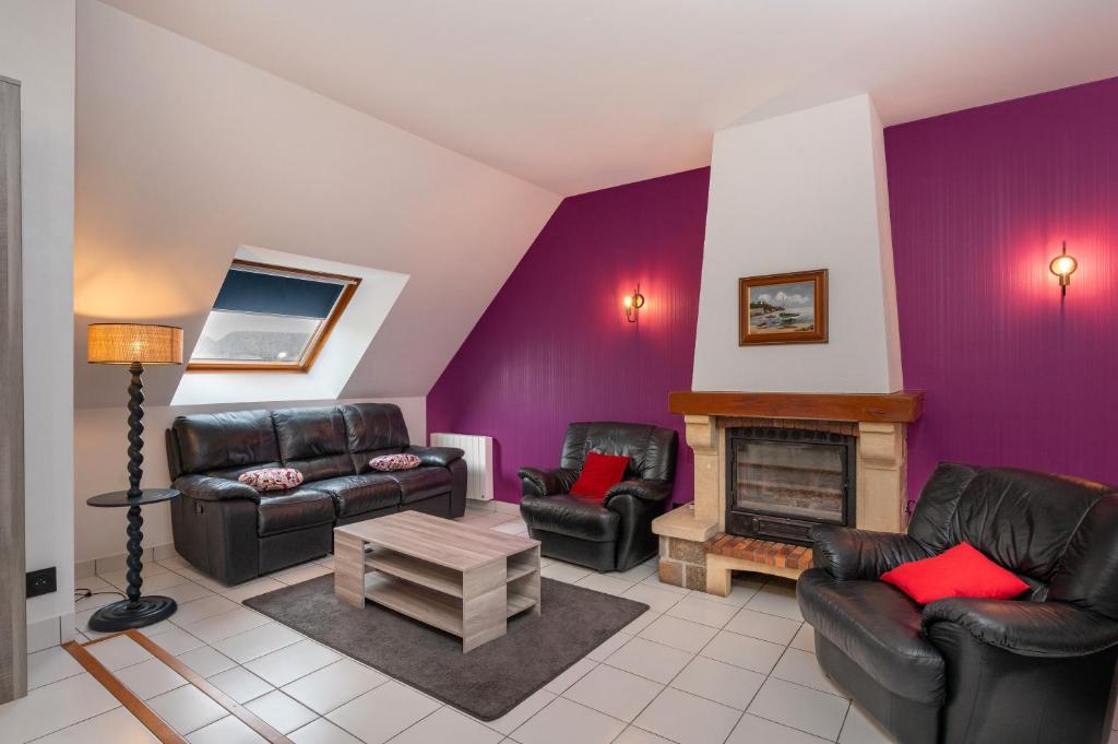 a living room with leather furniture and a purple wall at Maison entre terre et mer in Pluvigner